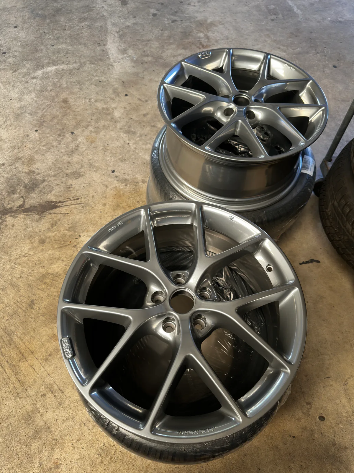 Zwei silbergrau pulverbeschichtete BBS-Felgen mit Mehrspeichen-Design auf dem Werkstattboden