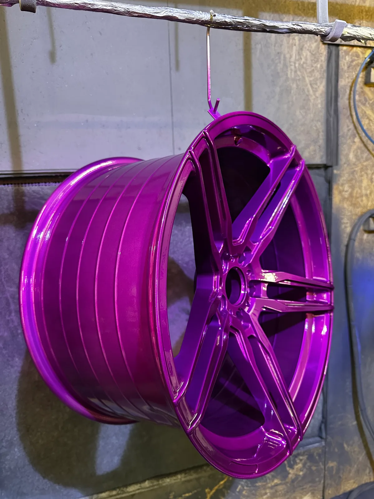 Kräftig violett glänzend pulverbeschichtete Felge mit konkaven Speichen, hängend in der Kabine
