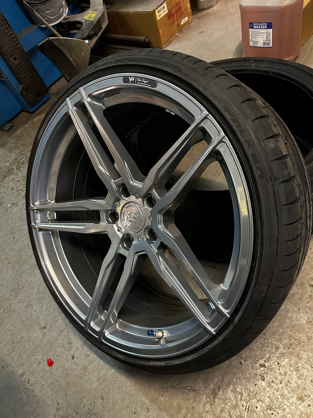 Silbergrau beschichtete Flow-Forged-Felge mit aufgezogenem Sportreifen in der Werkstatt