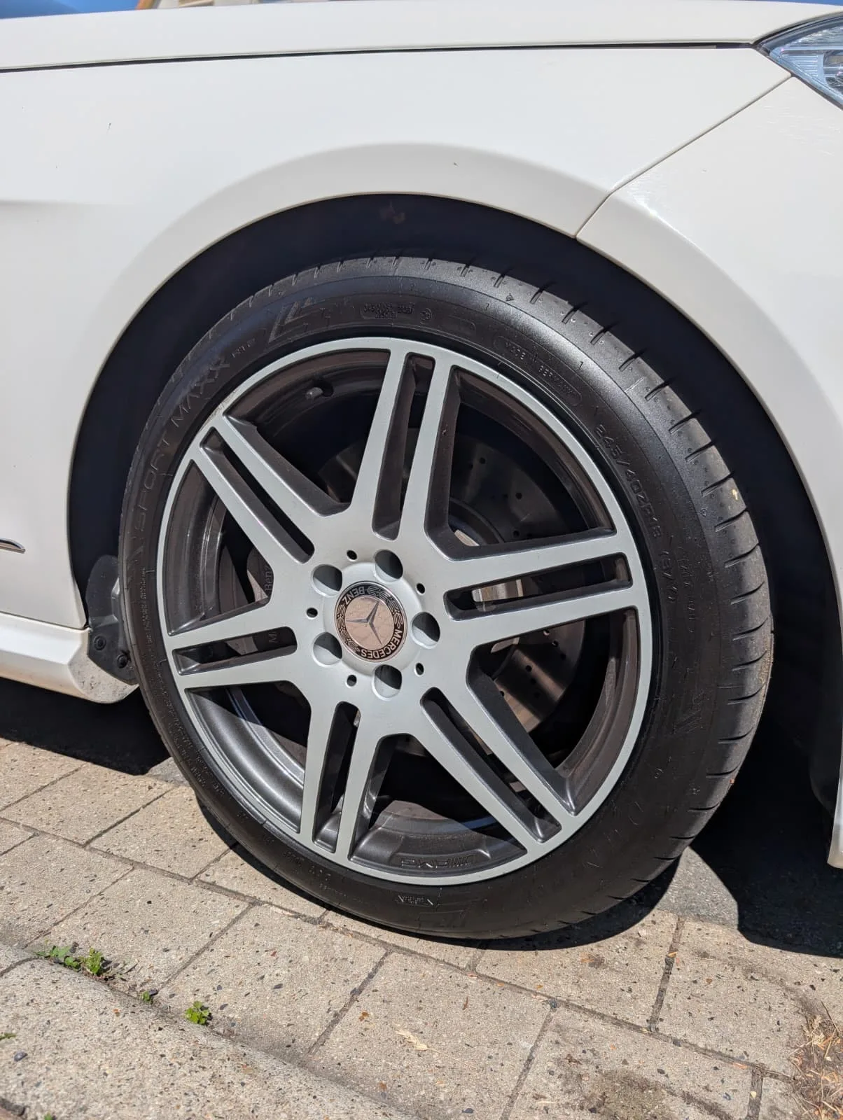 Fertig beschichtete Mercedes-AMG-Felge am weißen Fahrzeug montiert