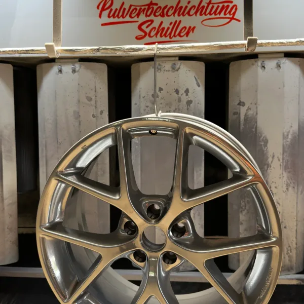 Pulverbeschichtete BBS-Leichtmetallfelge in Silbergrau, hängend in der Pulverkabine von Pulverbeschichtung Schiller